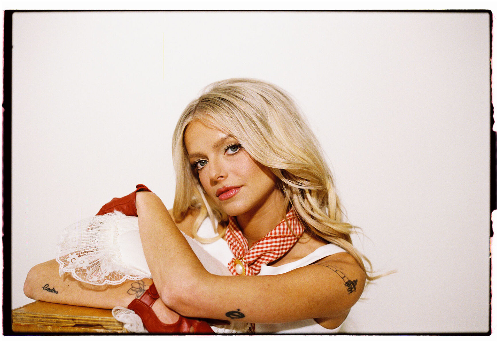 Carter Faith press photo artist poses with a white dress gingham bandana and red gloves against a white backdrop